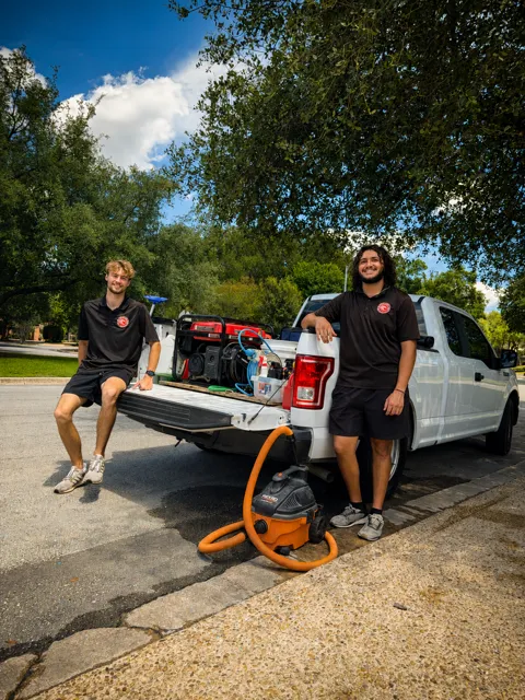 Detailing team with equipment beside a vehicle