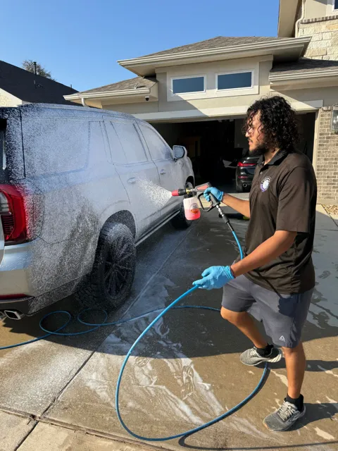 Detailer cleaning a vehicle with a pressure washer
